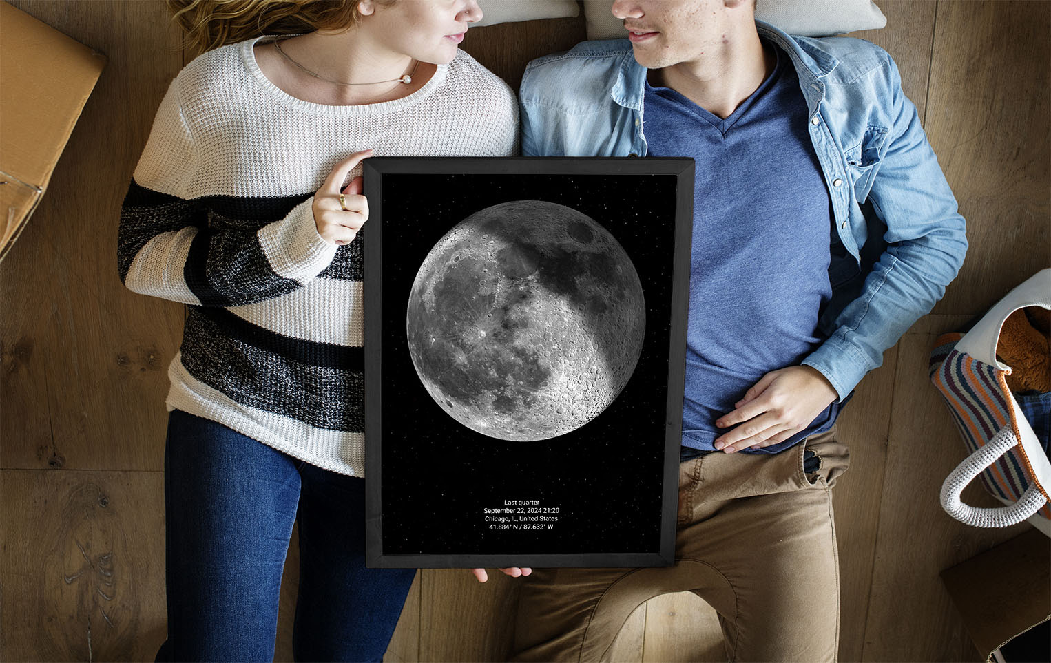 A couple holding a moon phase poster of the day they met.