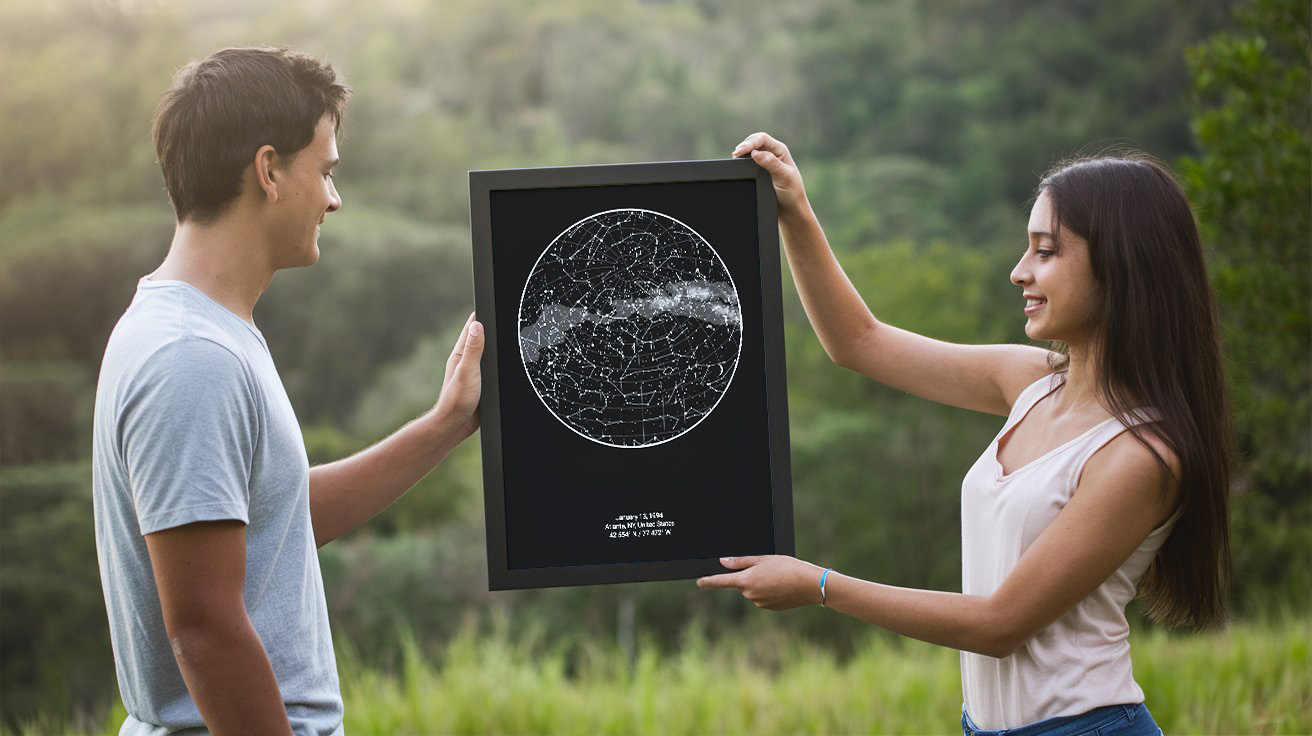 A photo of a girl holding a black frame with a star map poster, offering it to a guy standing beside her